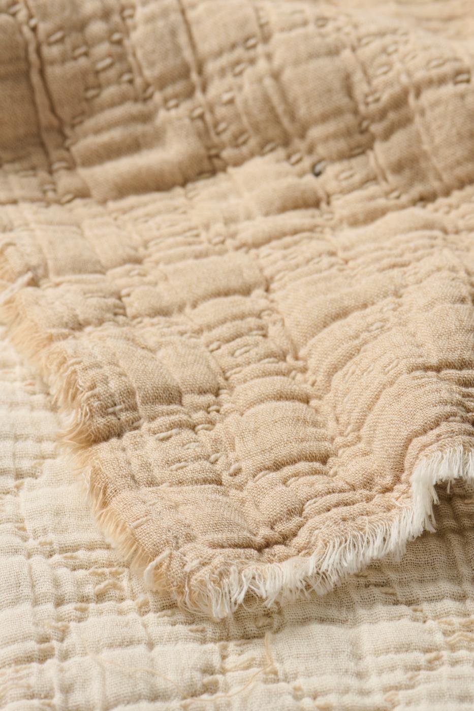 Close-up of a textured beige fabric with frayed edge