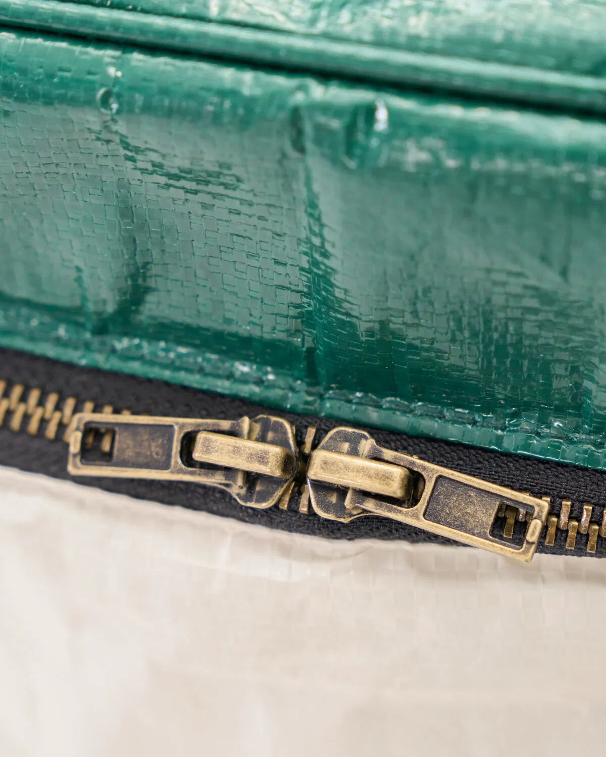 Close up of the zip on the sand and green insulated cooling picnic bag.