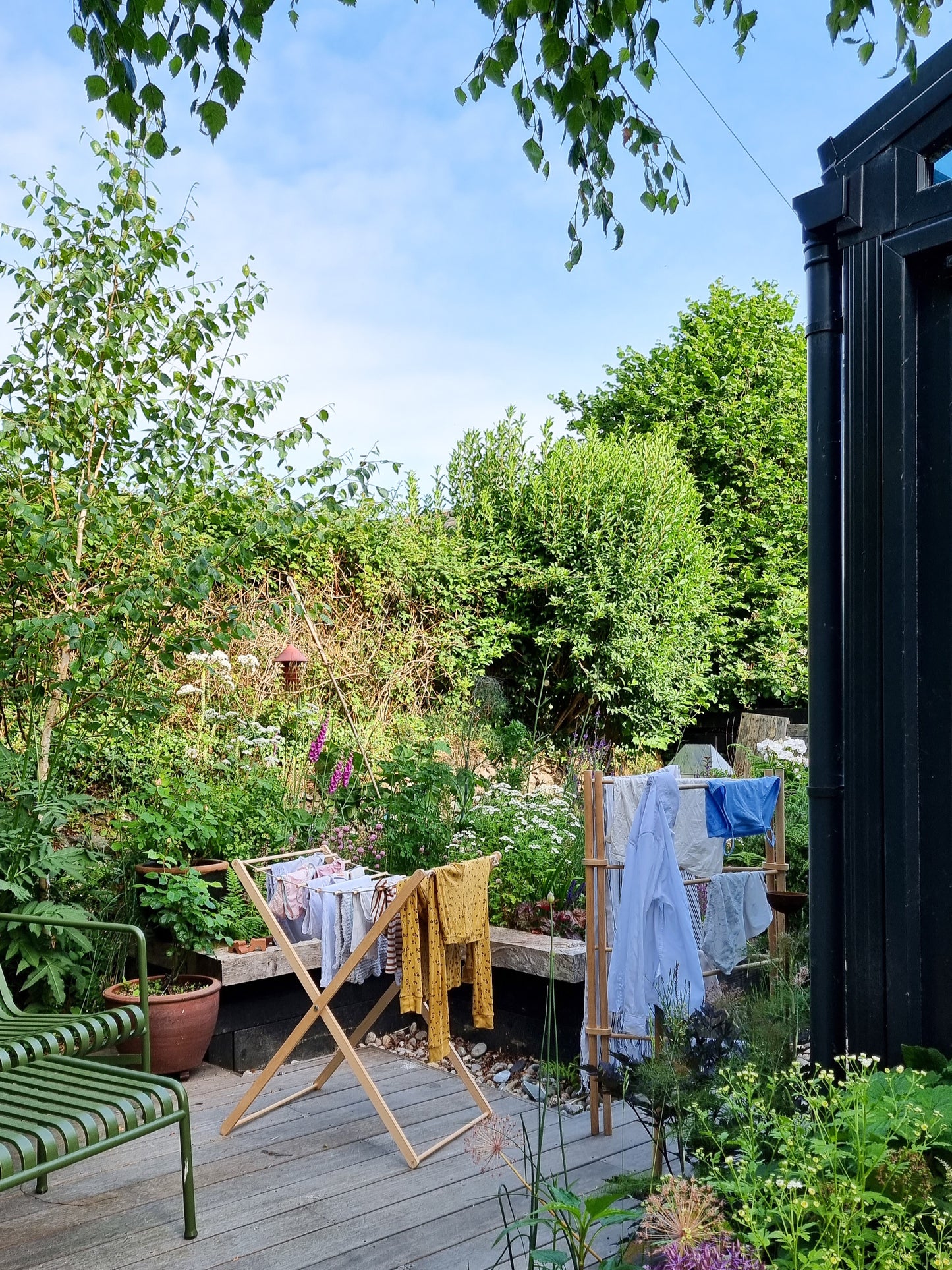 Foldable wooden wash drier airer with clothes drying on it, placed in a garden.