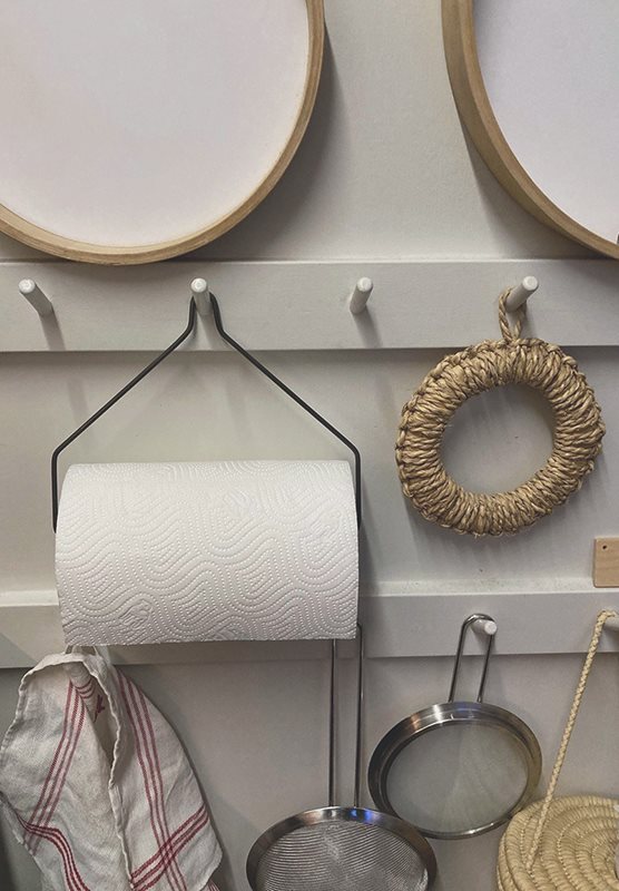 Paper towel holder on a peg rail within various other kitchen objects.