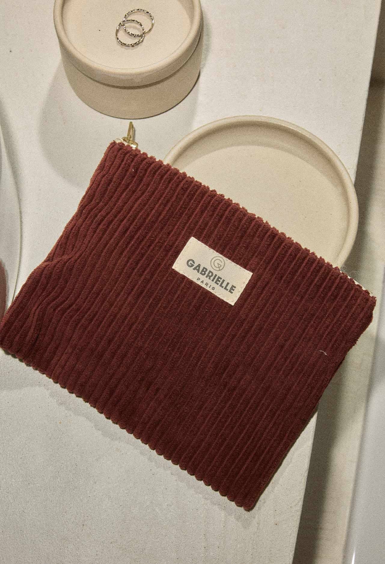 Red-wine coloured ribbed velvet pouch with a Gabrielle Paris label on a light background.