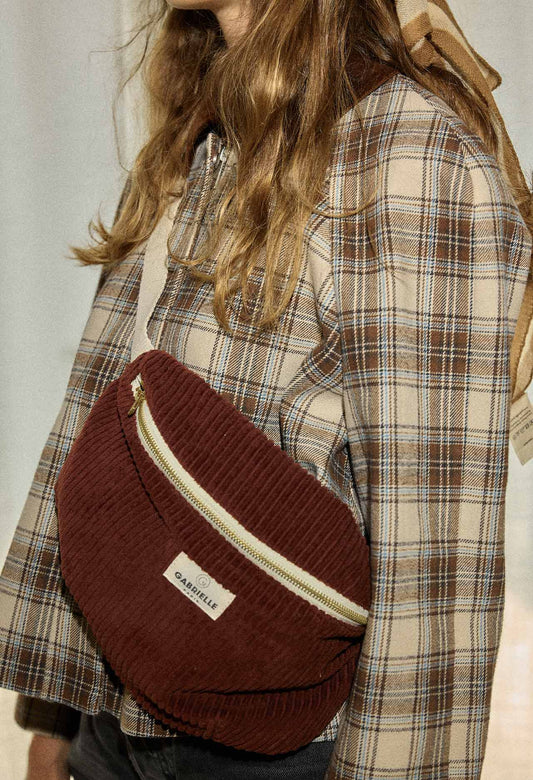 Person wearing a red-wine corduroy bag cross body over a plaid shirt.