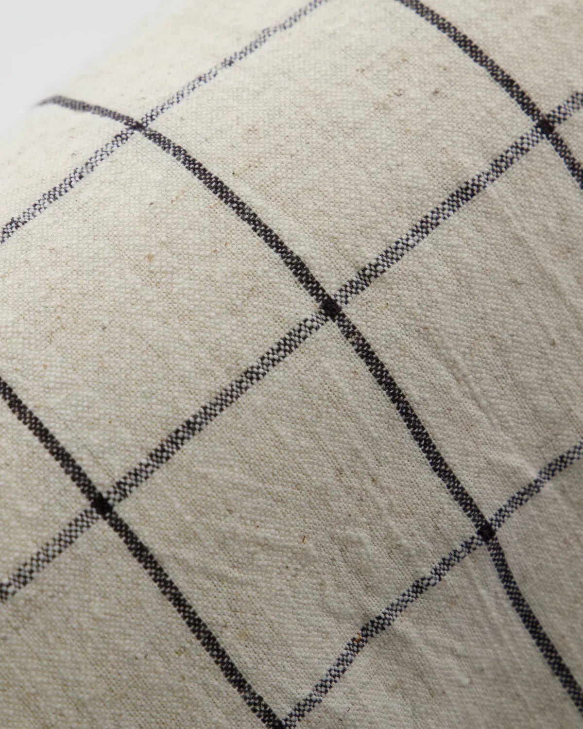A close up of the Join, off-white and black check cushion, showing the texture and colour.