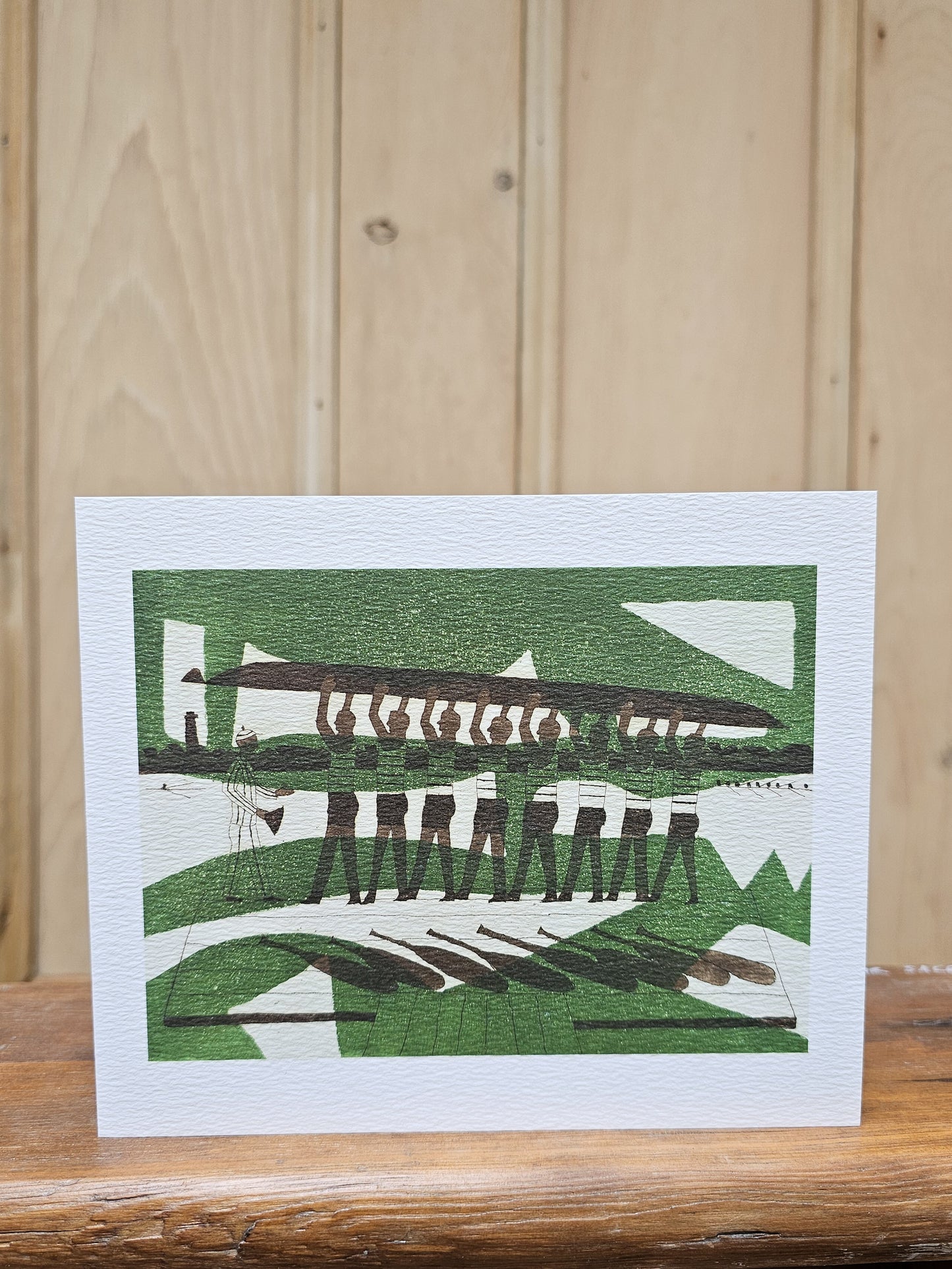 Greeting card reproducing Julian Trevelyan's linocut print The Rowers, showing a rowing eight carrying their boat above their heads in a bold green and brown composition