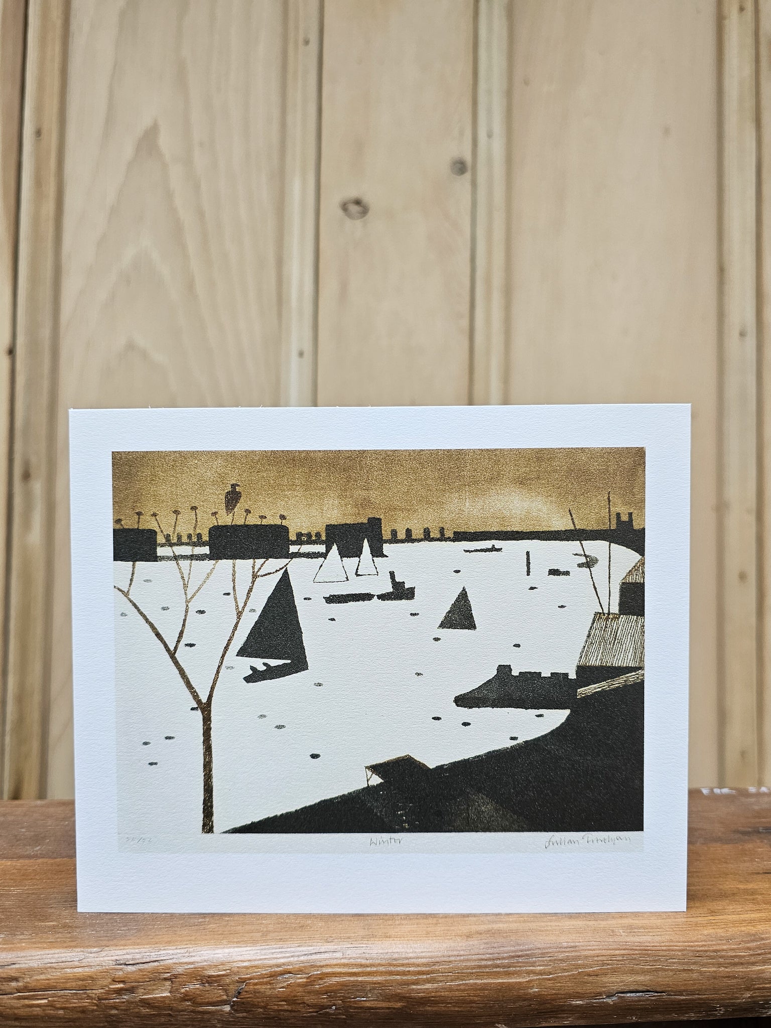 Greeting card reproducing Julian Trevelyan's 1974 print Winter, showing sailing boats on a frozen or misty river with a golden sky and dark industrial skyline