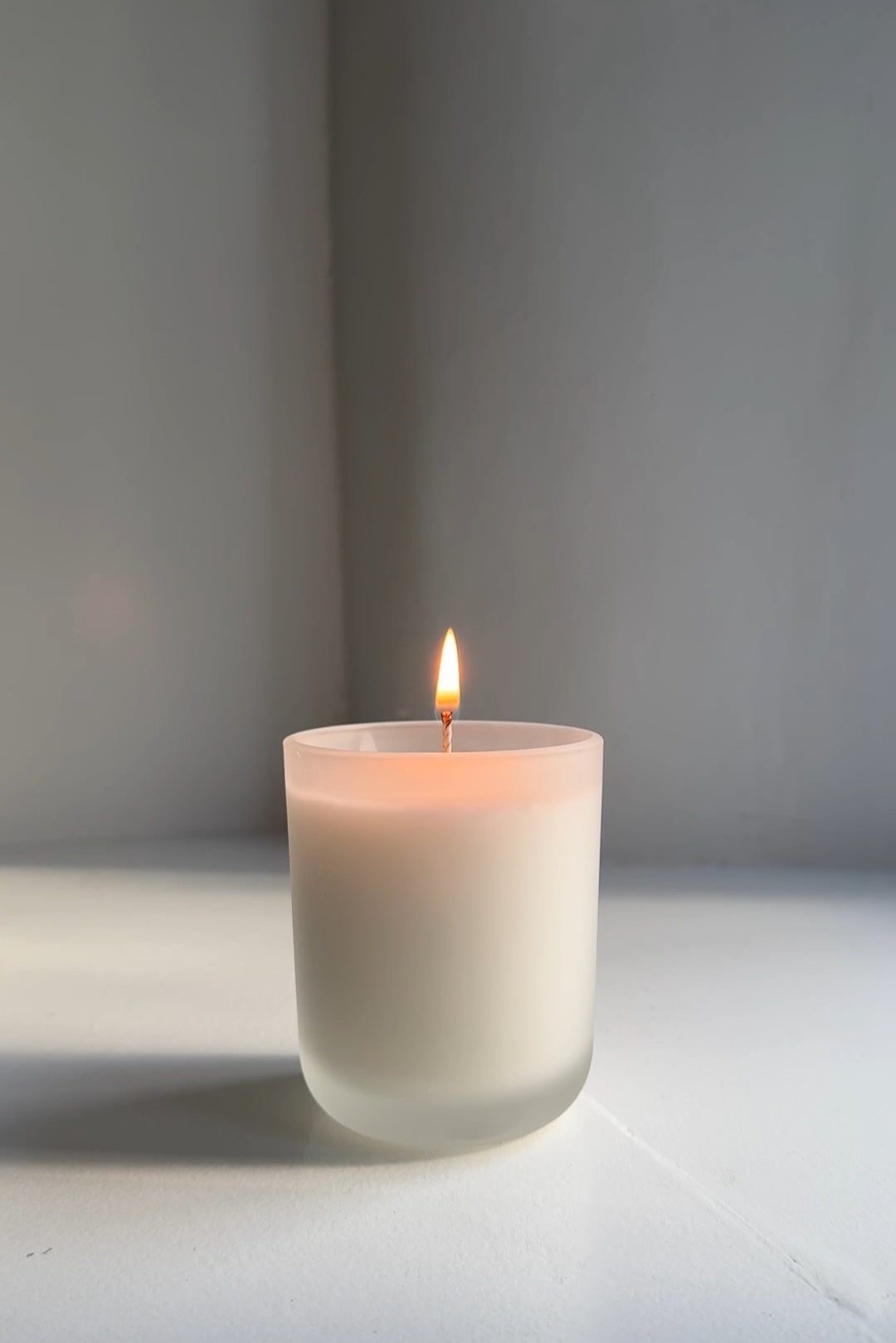 Kleensoaps coconut wax candle in a frosted glass jar, burning with a steady flame