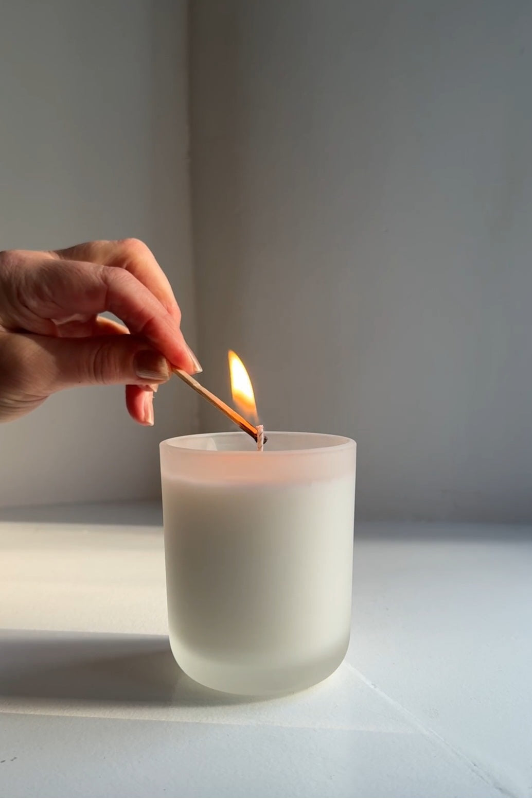 Lighting a Kleensoaps coconut wax candle in a frosted glass jar with an extra long match