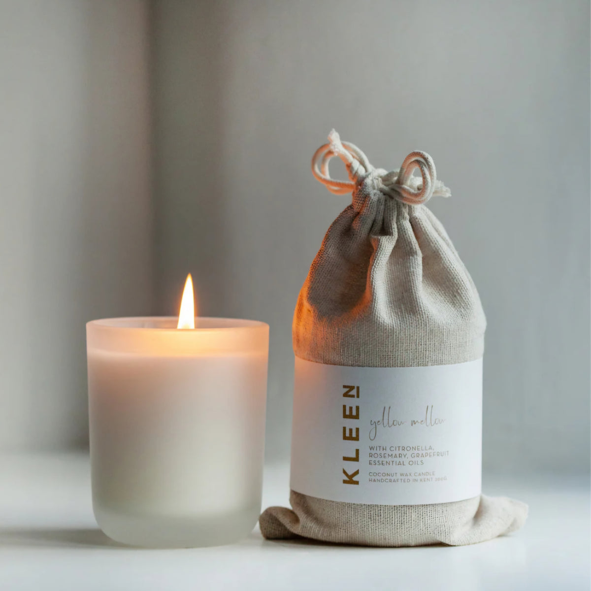 Kleensoaps coconut wax candle in a frosted glass jar, burning with a steady flame