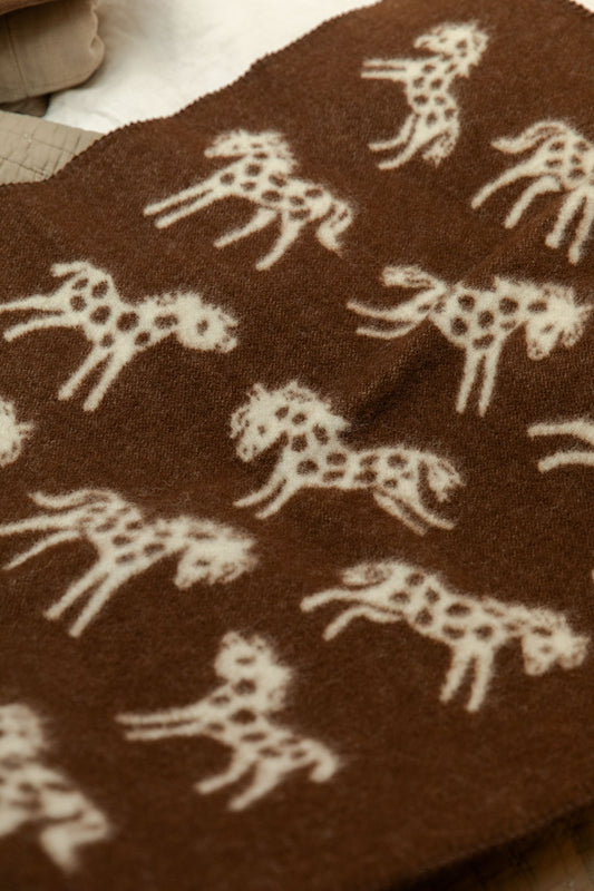 Close-up of Klippan Pony lambswool mini blanket chocolate brown side with cream running horse pattern detail.