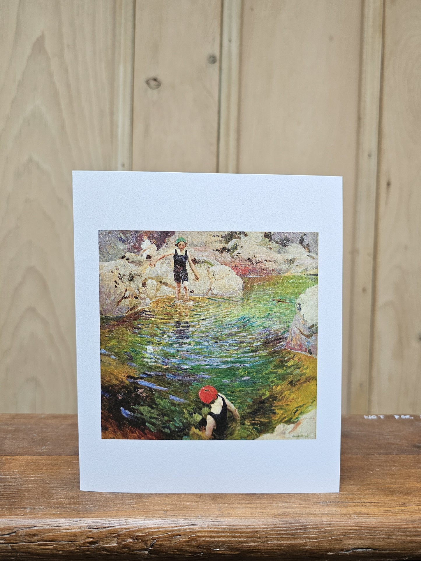 Greeting card reproducing Laura Knight's oil painting of two children paddling and exploring a clear green rock pool surrounded by boulders