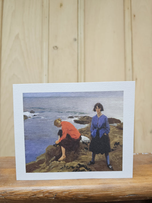 Greeting card reproducing Laura Knight's oil painting By the Shore, showing two women in colourful clothing standing on coastal rocks above a blue sea