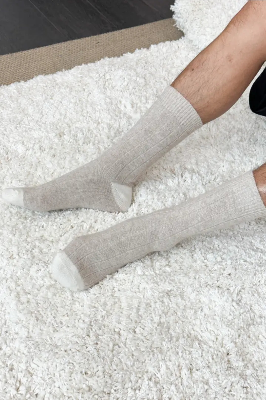 Person wearing fawn coloured socks on a white carpet.