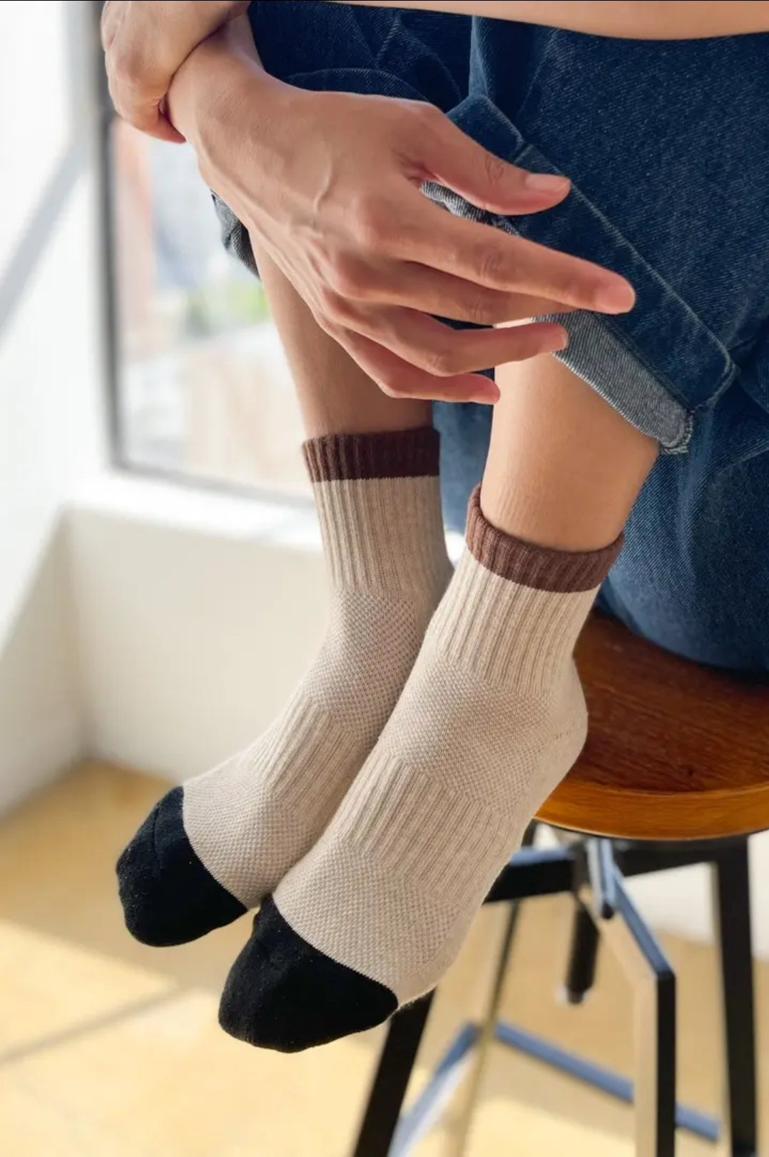 Person wearing beige socks with brown and black accents sitting on a chair.