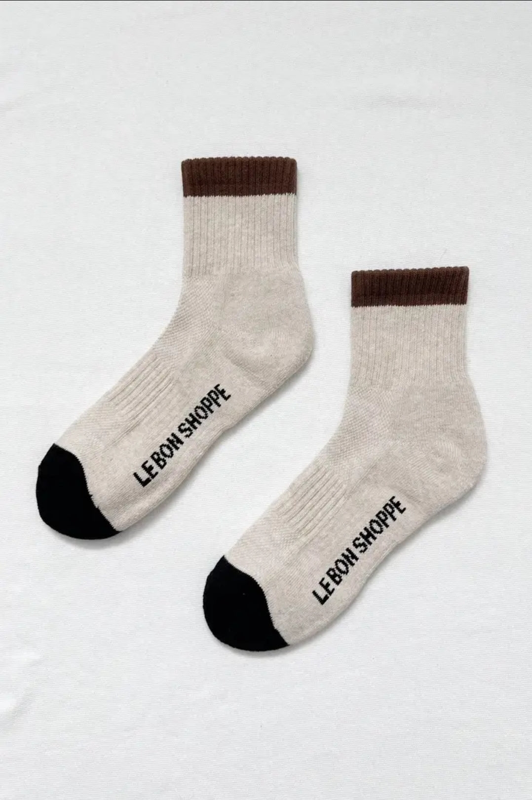 Pair of beige socks with brown cuffs and black toes on a white background, featuring 'Le Bon Shoppe' branding on the sole.