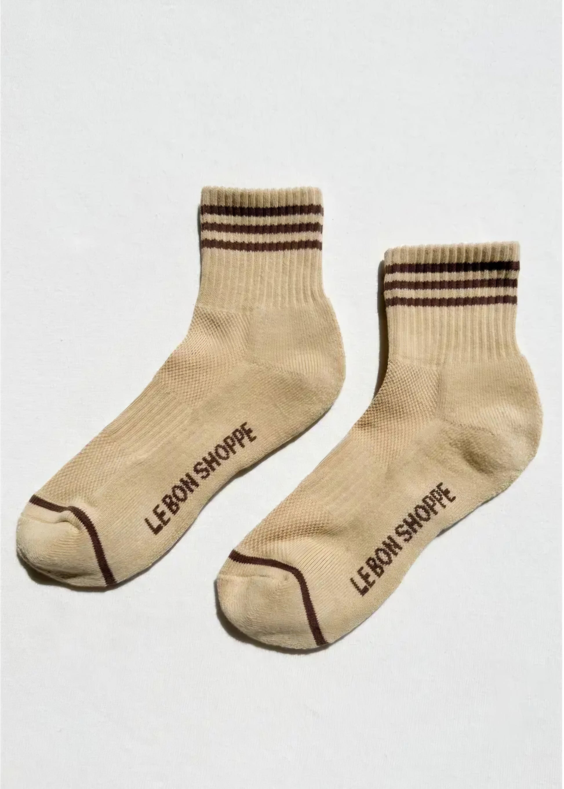 Light yellow socks with brown stripes and 'Le Bon Shoppe' branding on the sole on a white background.