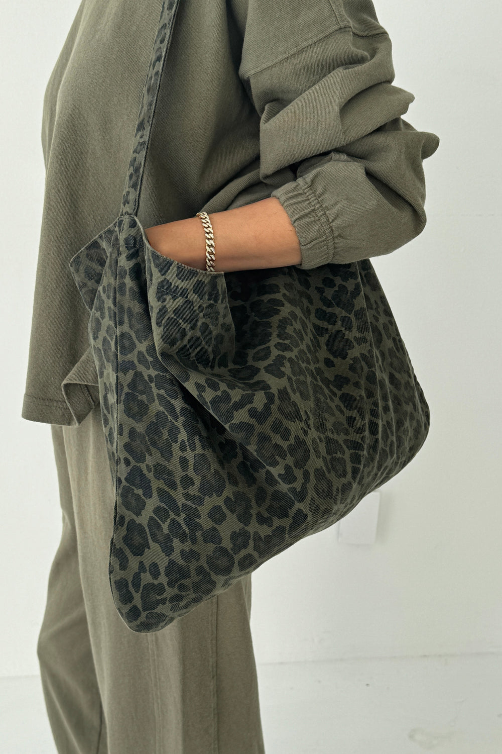 Le Bon Shoppe Happy Carry Bag in fern leopard canvas worn on shoulder with khaki outfit.