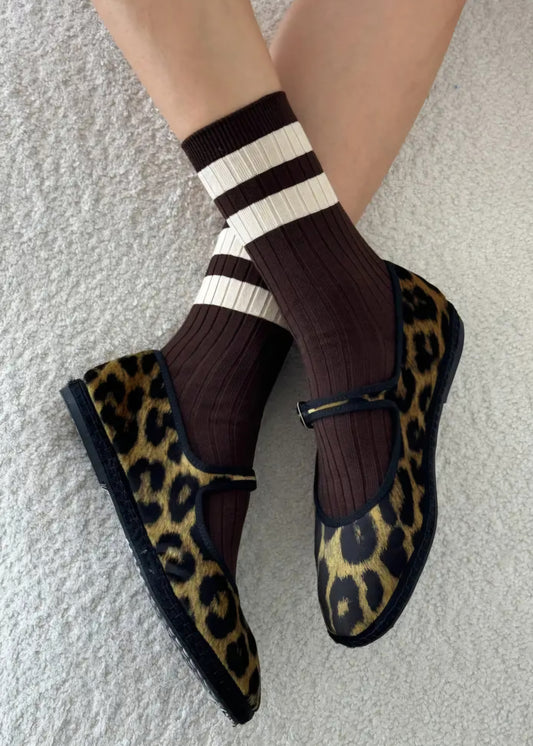 Leopard print shoes with striped socks on a neutral background.