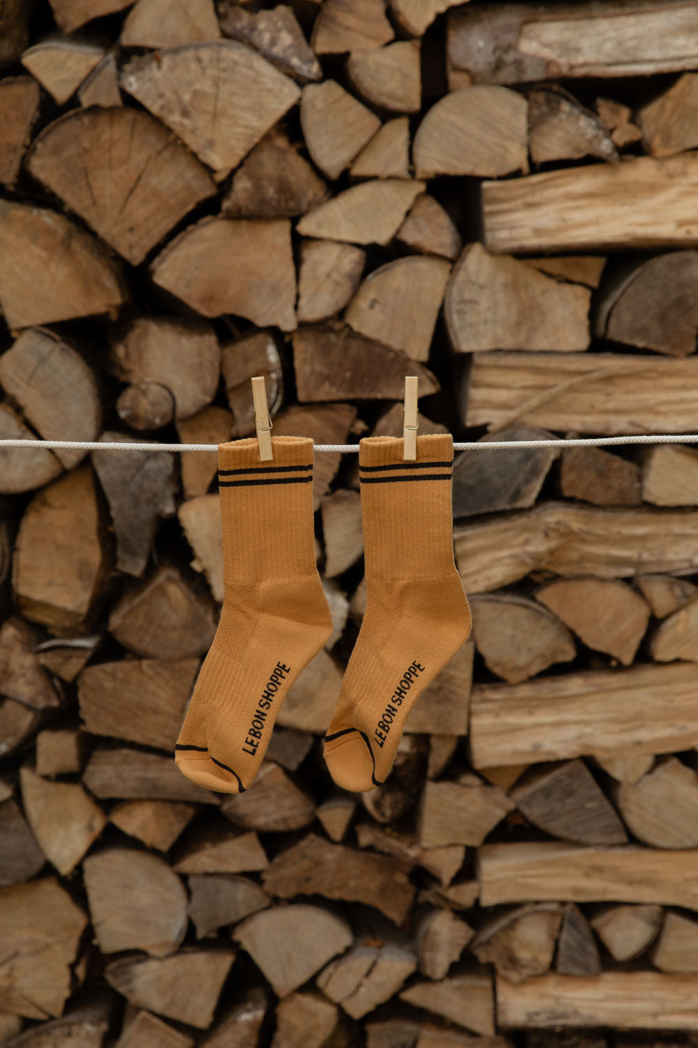 Le Bon Shoppe Boyfriend Socks in Biscotti with brown stripes pegged against stacked wood