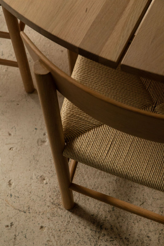 Oak Longworth dining chair with a woven paper cord seat beside a round oak table