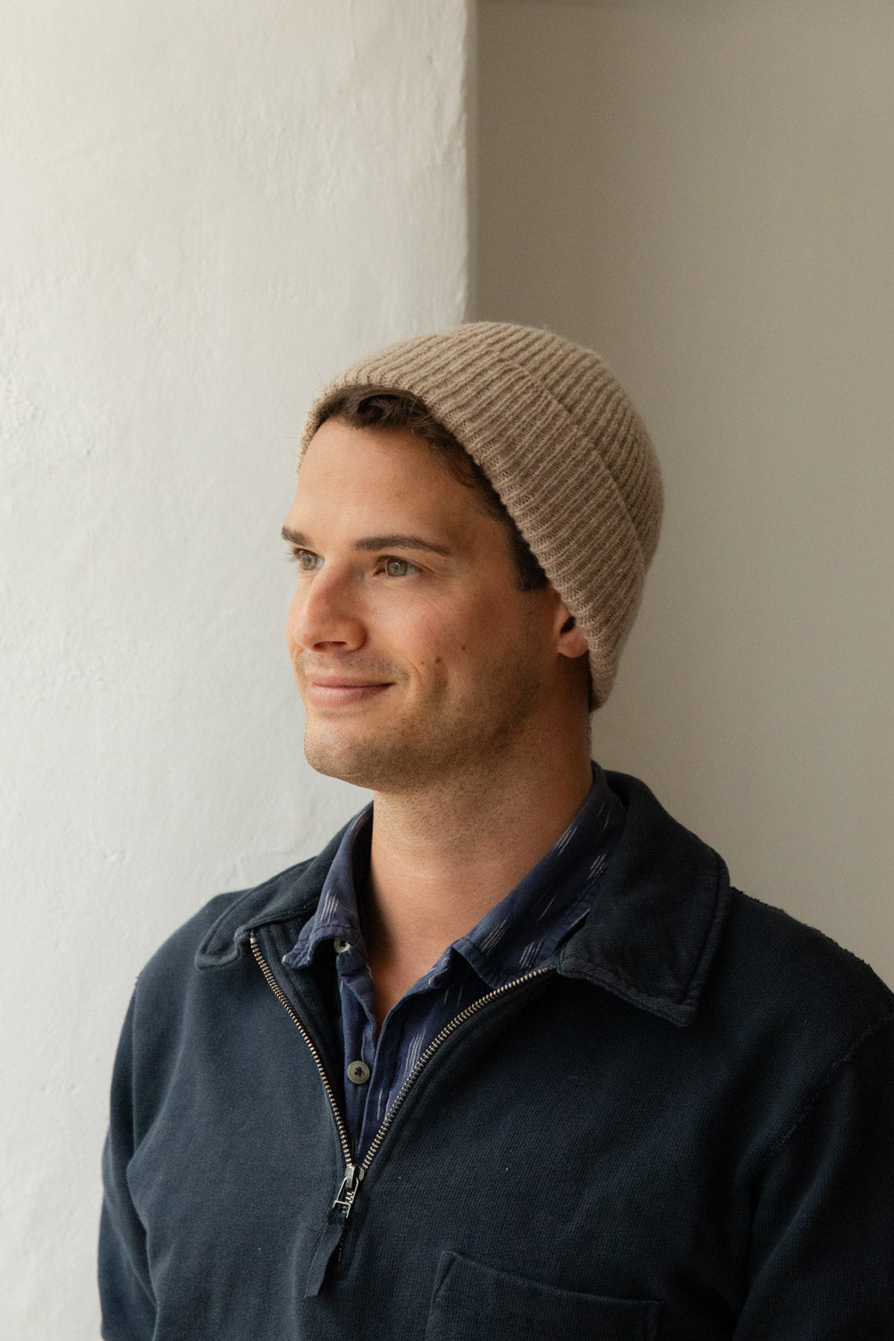 Man wearing an oatmeal heritage wool beanie against a white wall