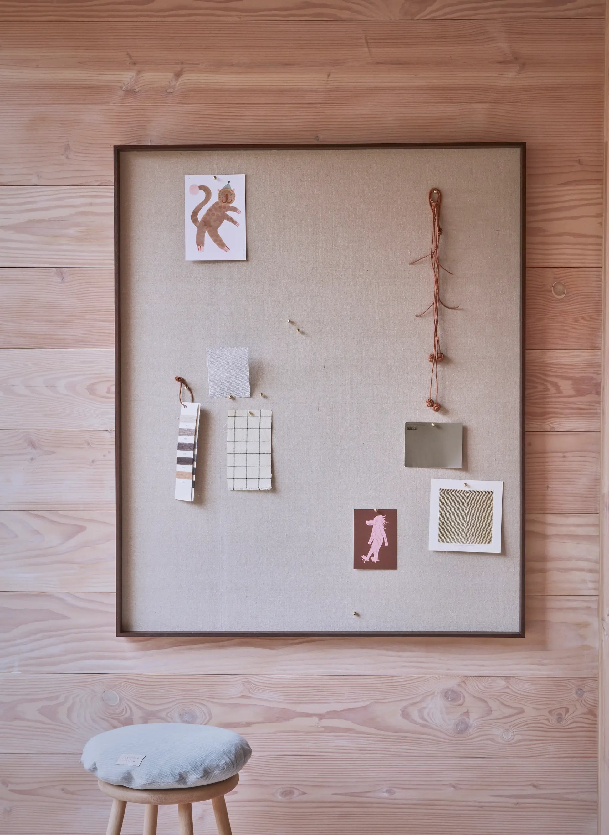 OYOY Peili Notice Board large with dark wood frame styled with postcards and fabric swatches on pine-clad wall