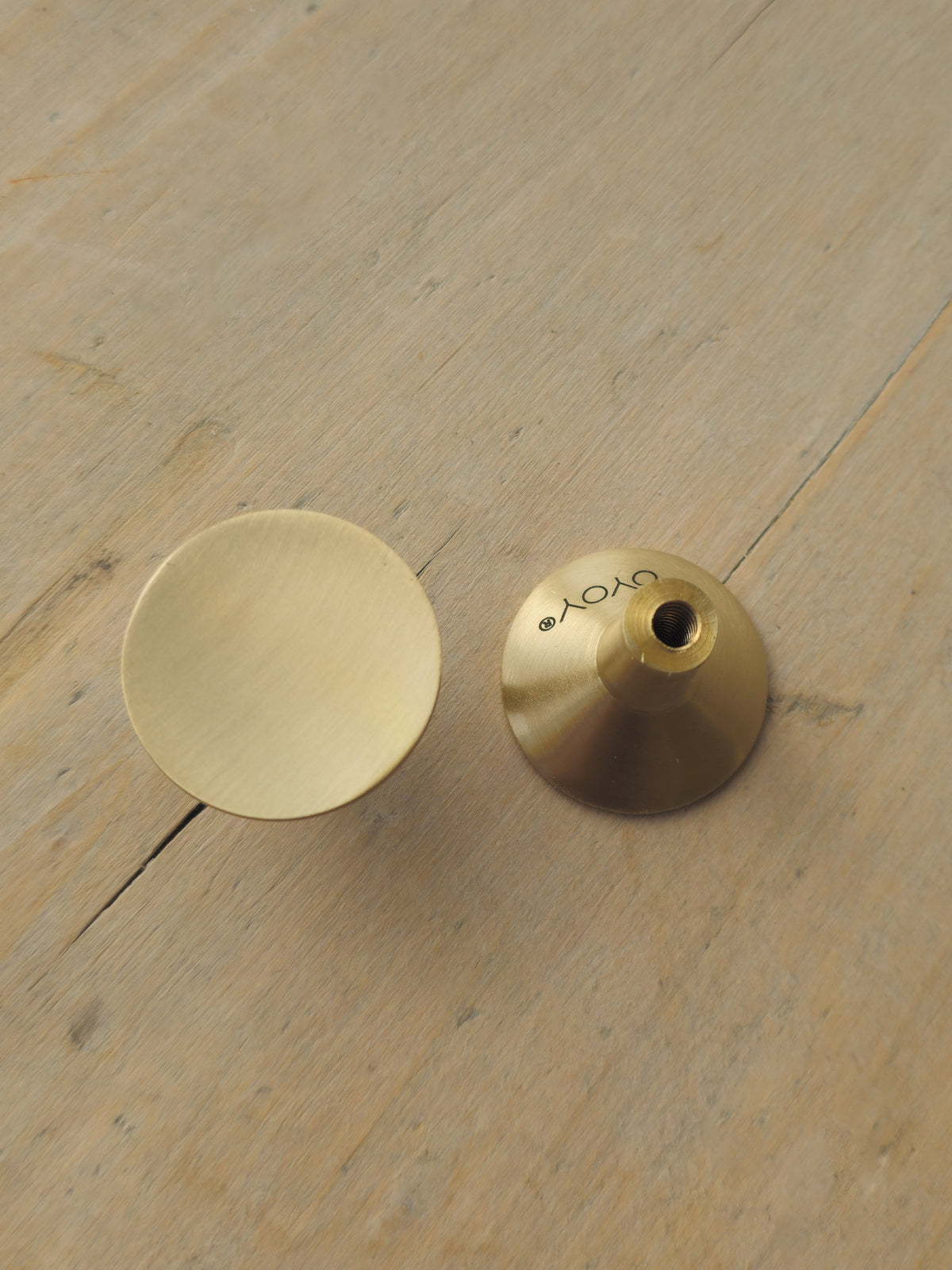 A brass mouthpiece and mouthpiece cap, both in a brushed gold finish, displayed on a light-colored wooden surface. The cap has the brand name 'YAMA' printed on it.