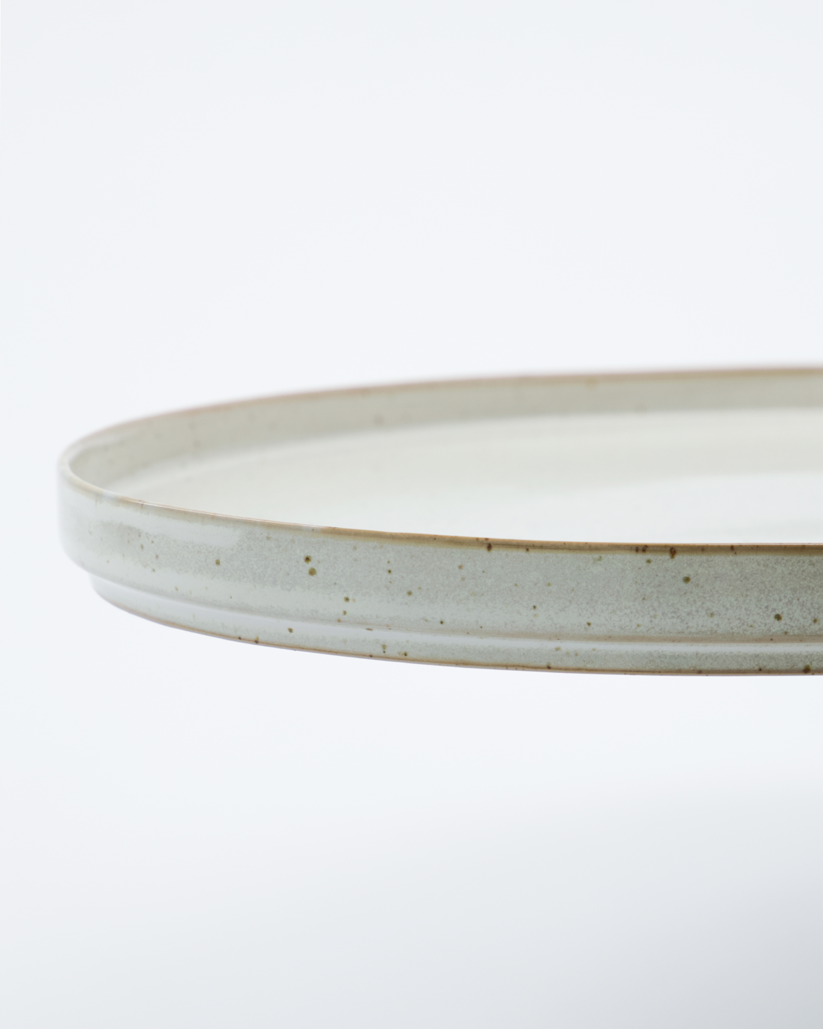 A close up of a speckled white serving dish on a white background.