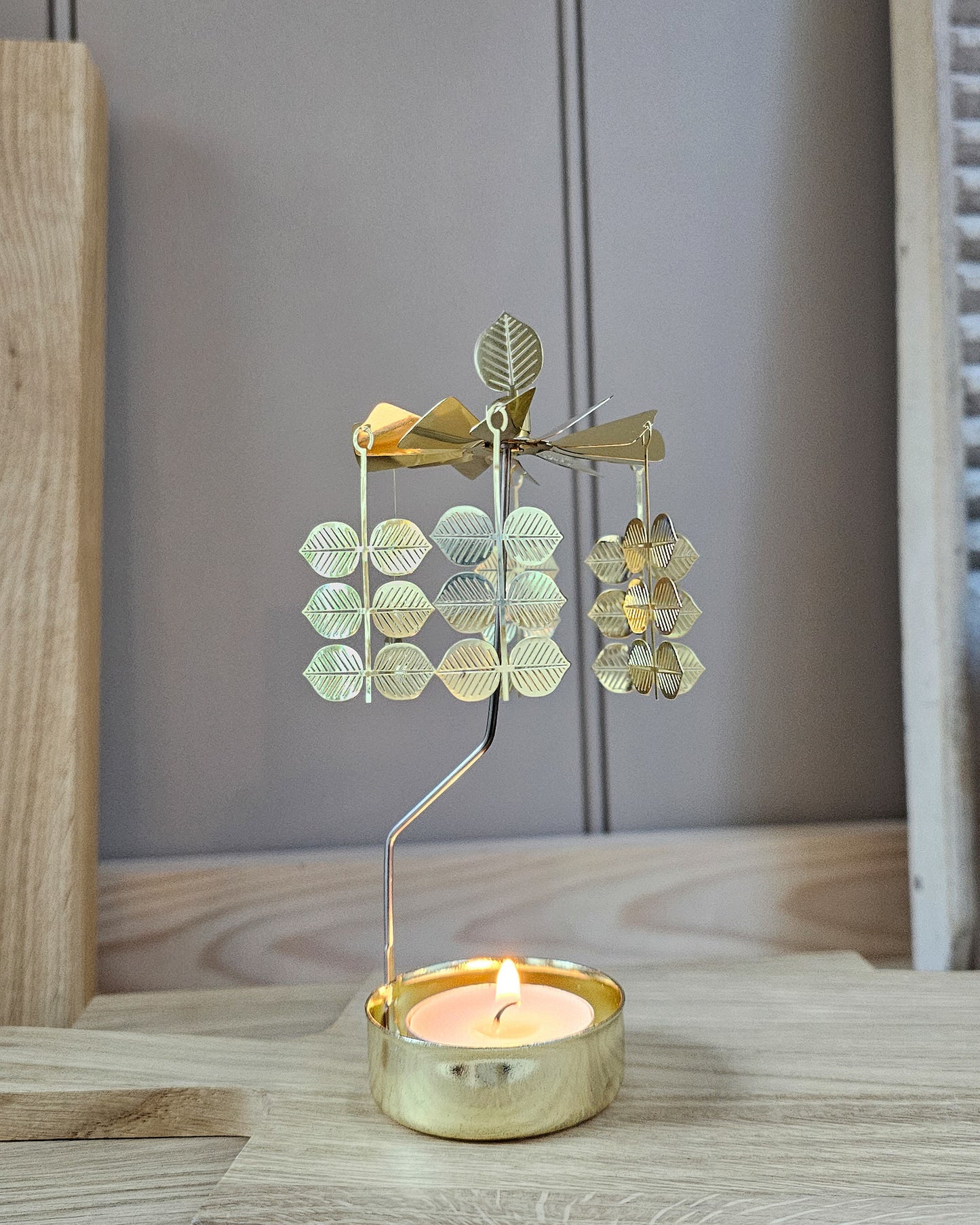 Decorative metal candle holder with leaf design on a wooden surface.