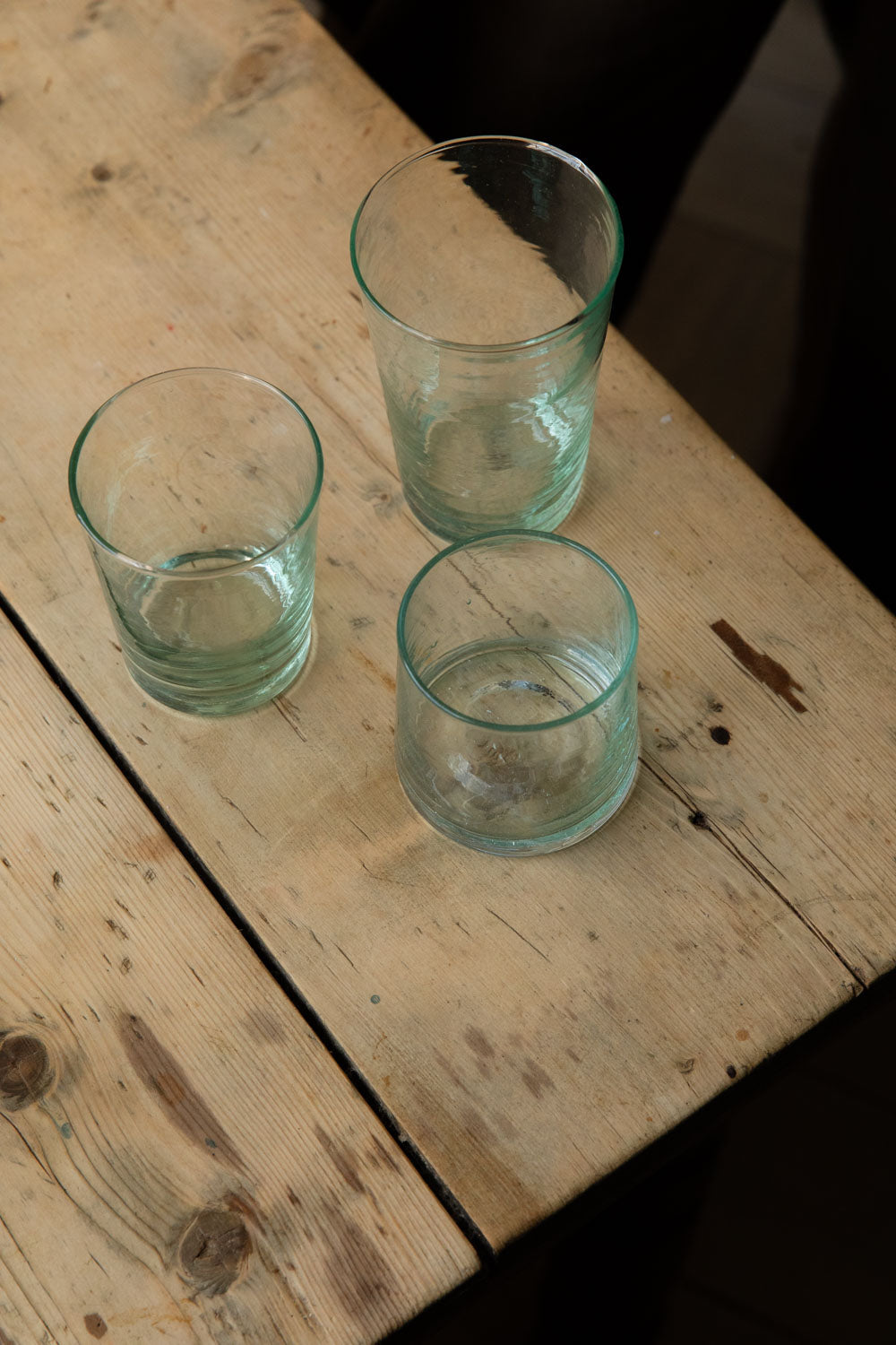 Tall and short Meknes recycled glass tumblers grouped on the corner of a wooden table