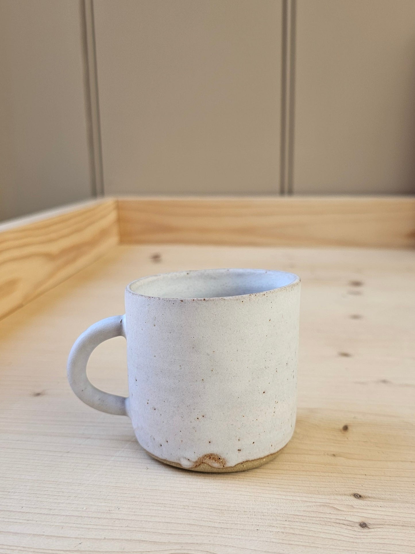 White ceramic mug on a wooden surface with a neutral background