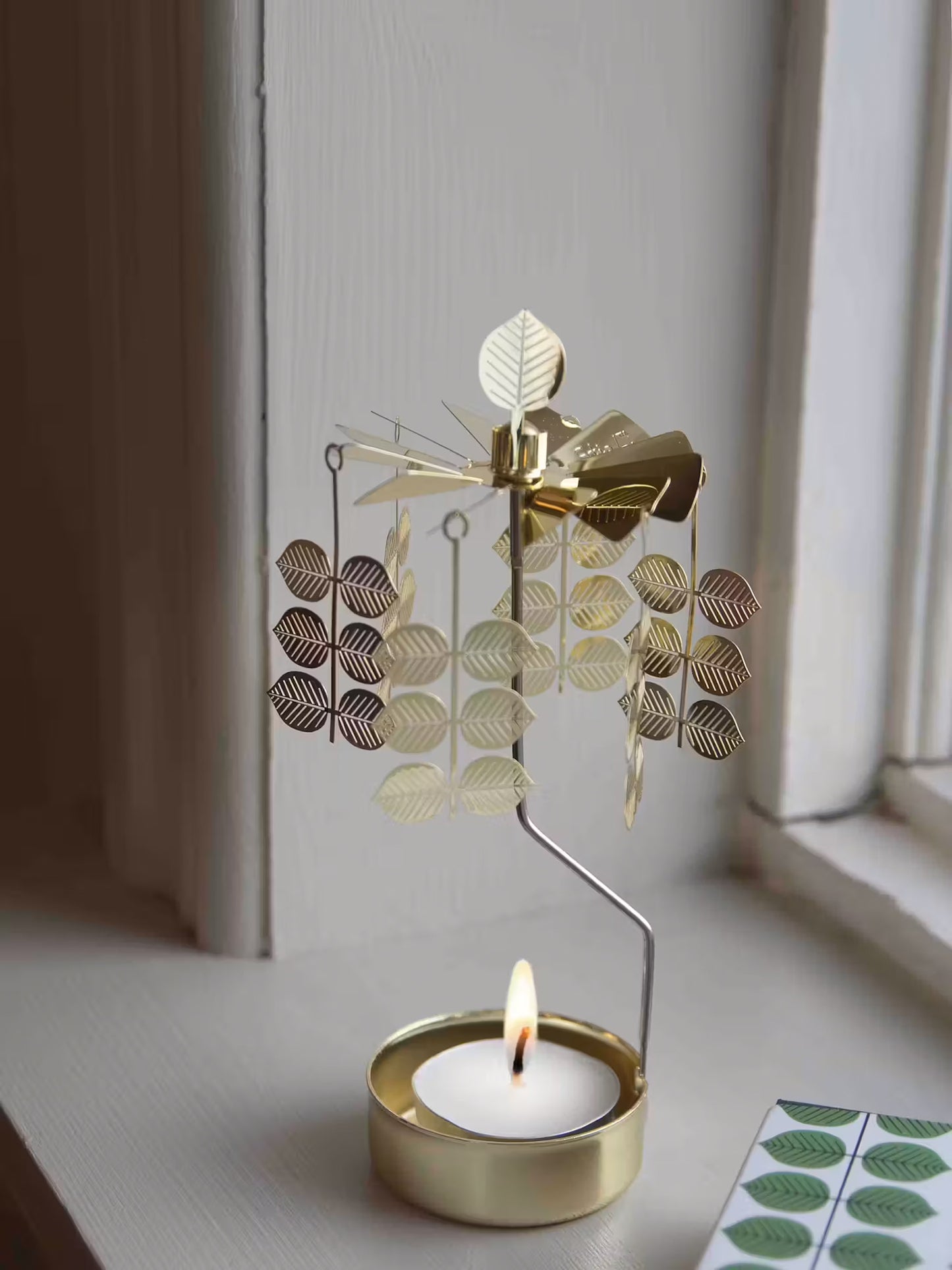Decorative gold metal tealight holder with a metal leaf details.