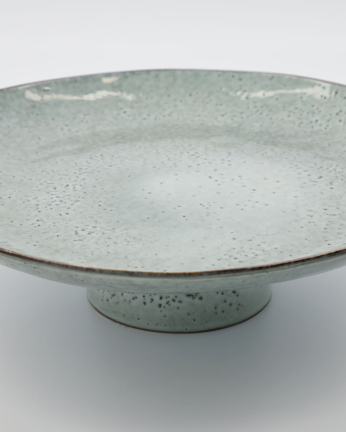 Close up of a rustic cake stand, with a beautiful blue/grey glaze.