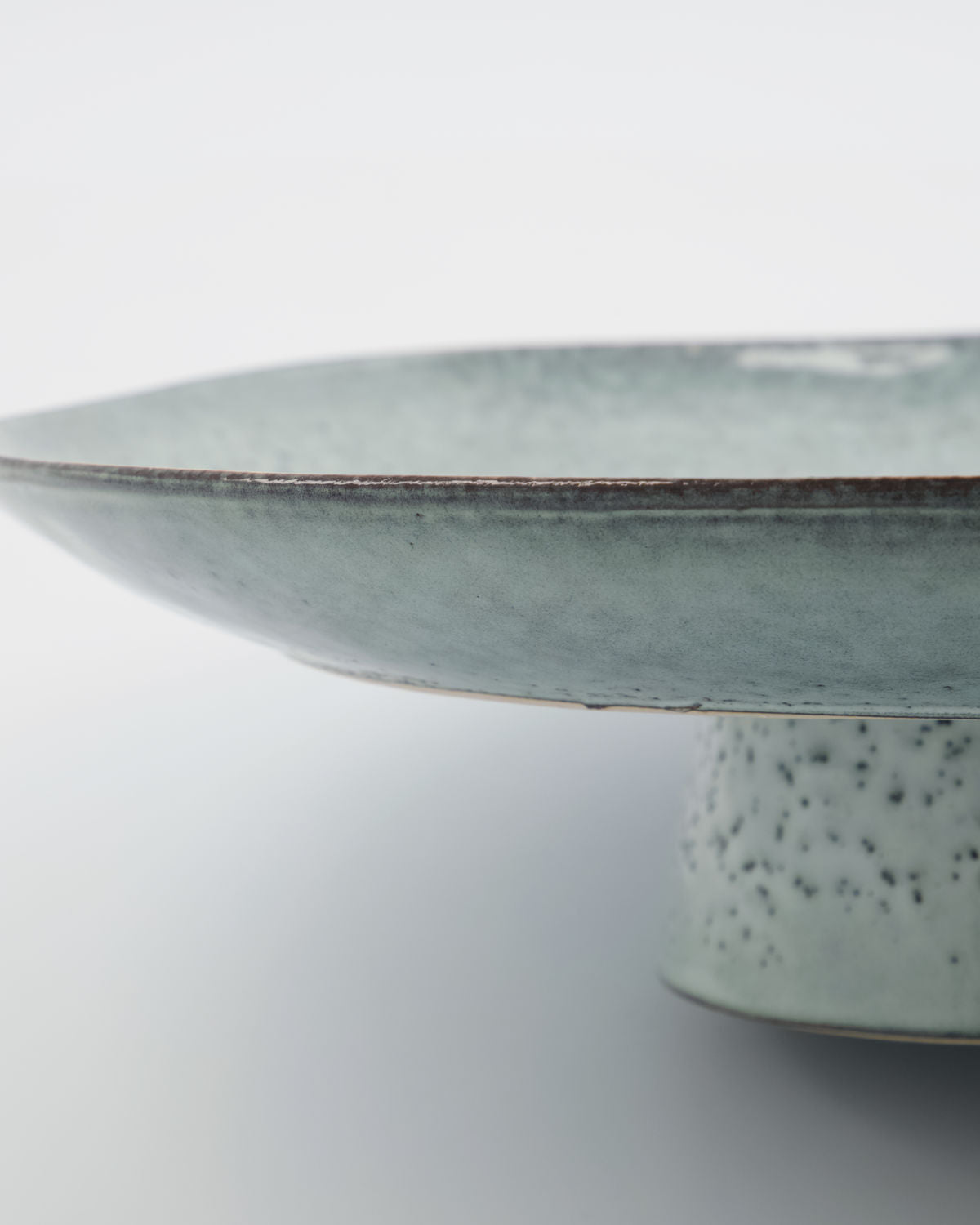 Close up of a rustic cake stand, with a beautiful blue/grey glaze.