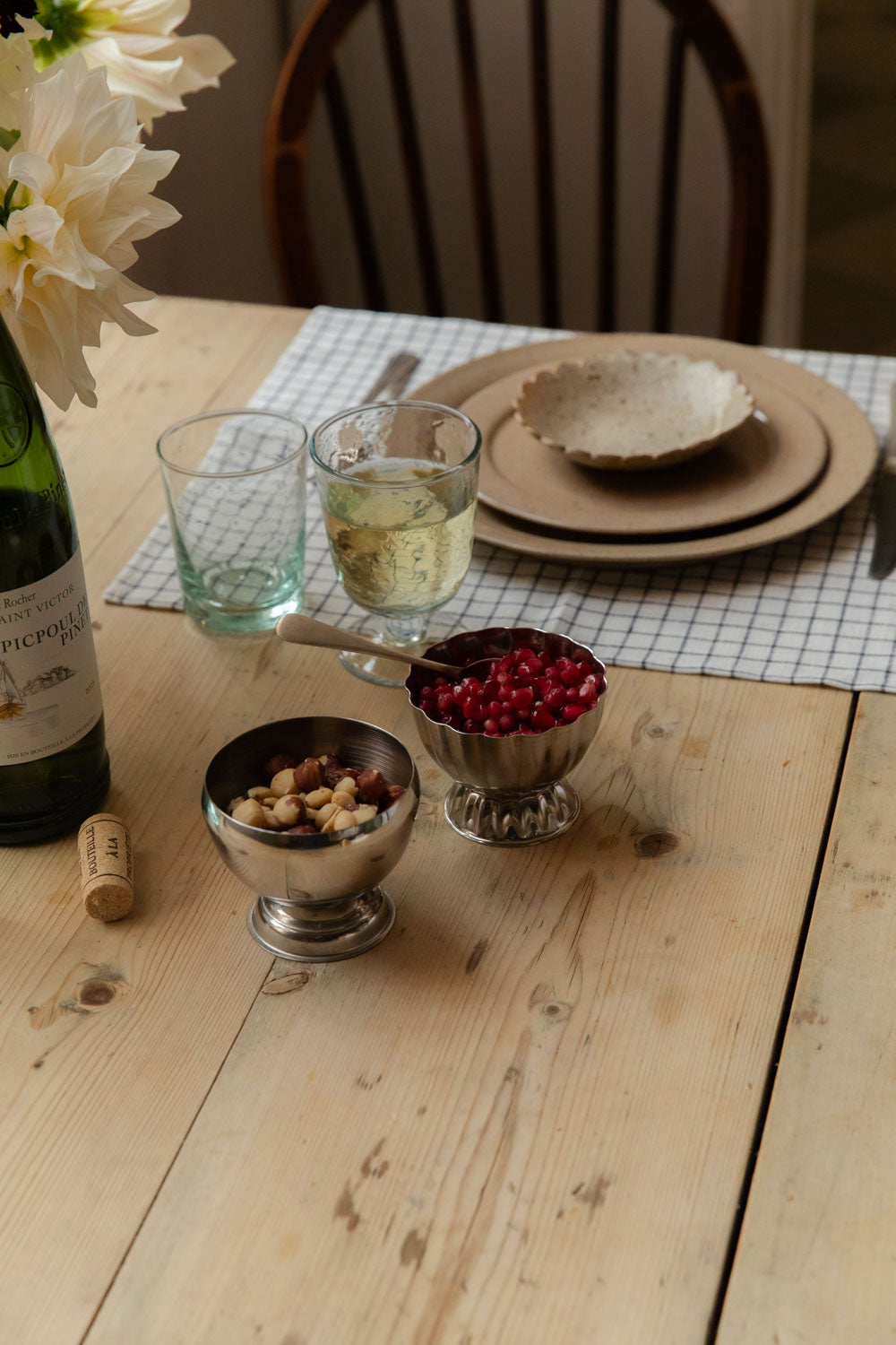 Table laid for supper with stainless steel ice cups of nuts and pomegranate, wine and speckled plates