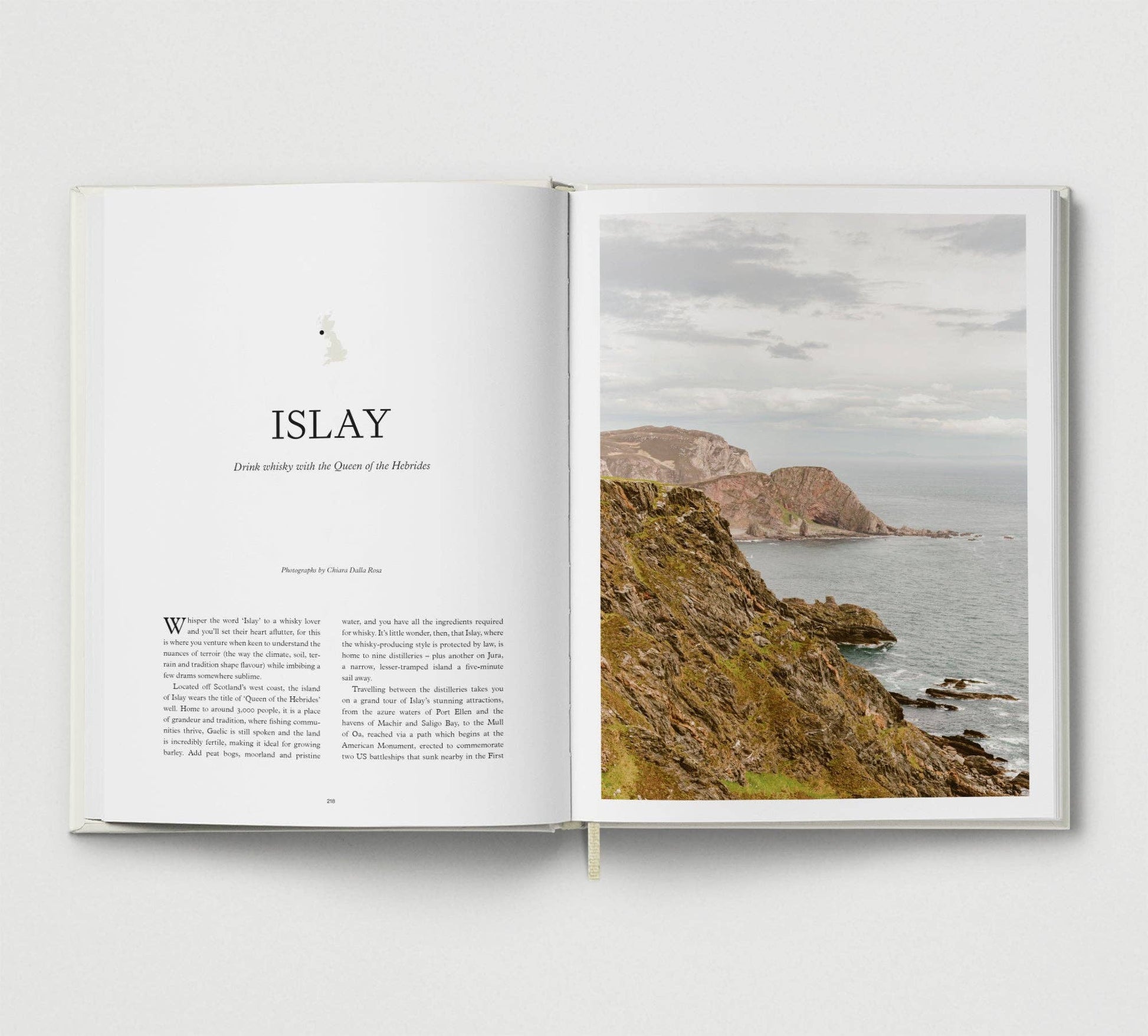 Open book with a photograph of a coastal landscape on the right page and text on the left page.