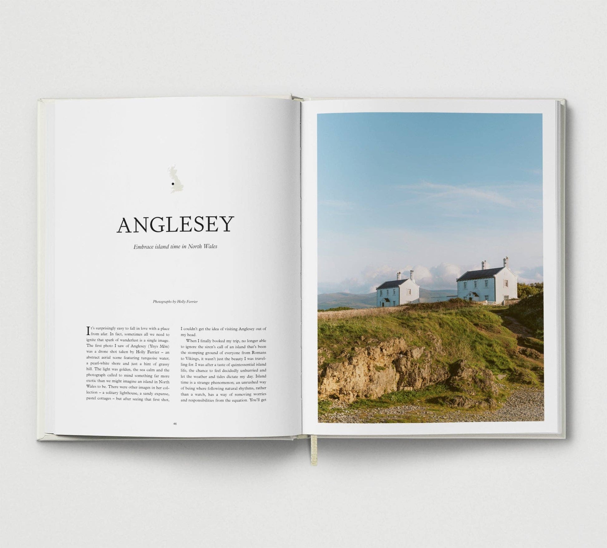 Open book showing a photograph of houses on a cliff with the word 'ANGLESEY' above.