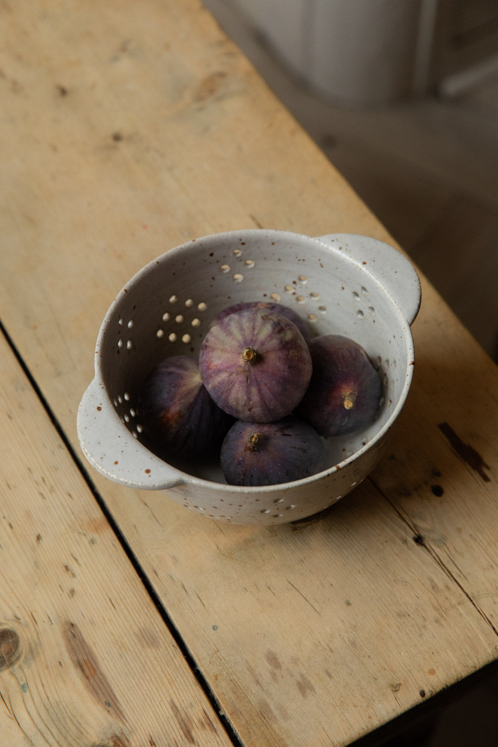 Ripe purple figs in a white speckle stoneware berry bowl with handles