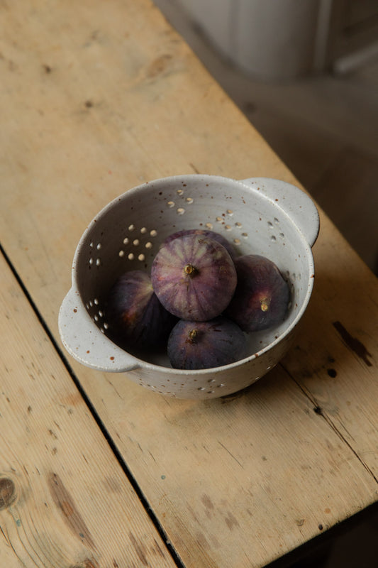 Ripe purple figs in a white speckle stoneware berry bowl with handles