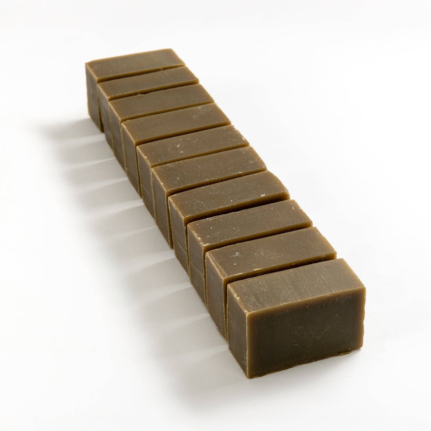 Row of spirulina seaweed soap brick cut into smaller pieces on a white background.