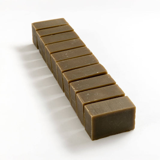 Row of spirulina seaweed soap brick cut into smaller pieces on a white background.