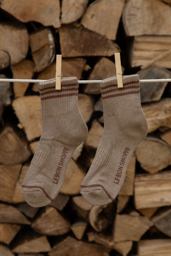 Le Bon Shoppe Girlfriend Socks in Hazelwood, taupe with brown stripes, pegged against firewood