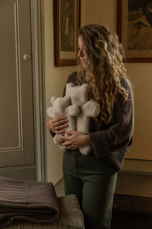 Woman hugging an armful of cream teddy sheepskin hot water bottles in a panelled room