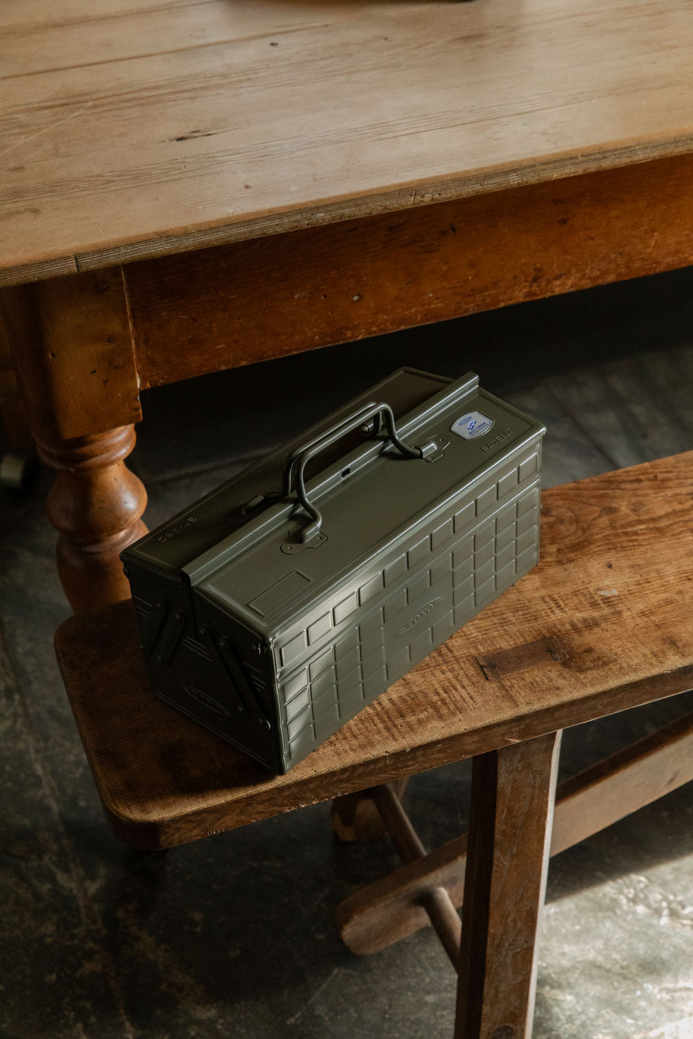 Olive green Toyo two-tier steel toolbox on an old wooden bench