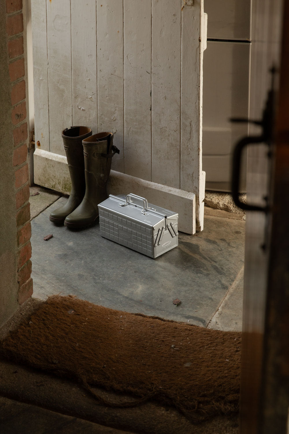 Silver Toyo cantilever toolbox beside green wellies at a back door