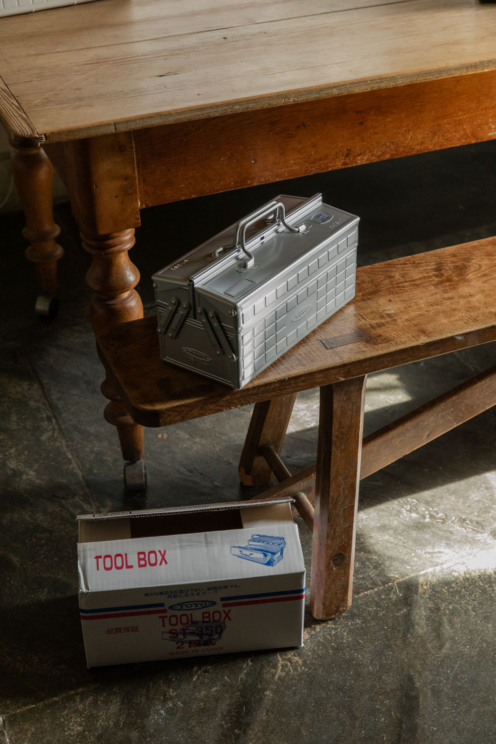 Silver Toyo cantilever toolbox on a bench with its retro printed box below