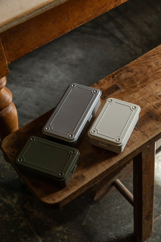 Small Toyo T-150 and T-190 steel boxes in moss green, white and silver on a wooden bench