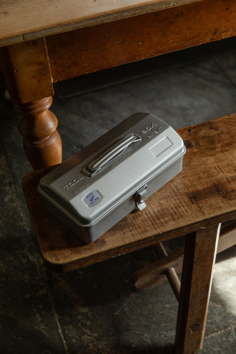 Grey Toyo steel toolbox with a single carry handle on a rustic bench