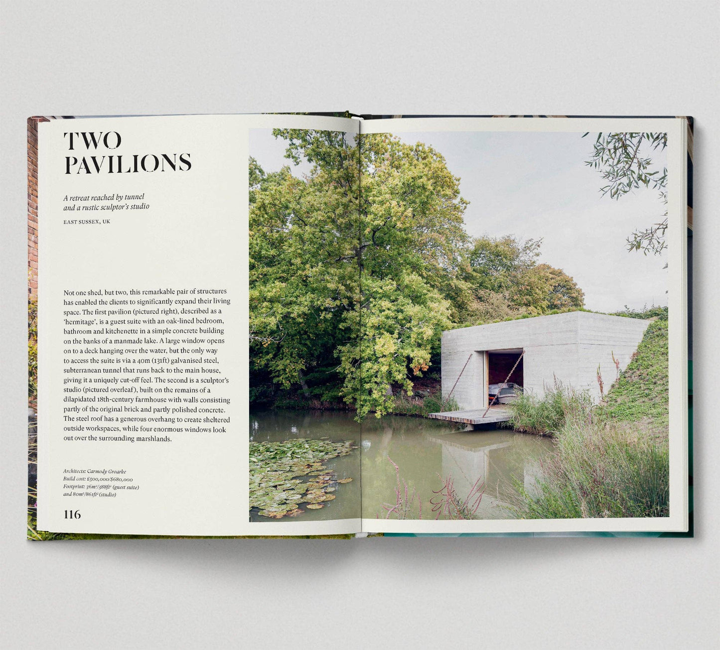 Open book showing a photograph of a modern building by a body of water with trees in the background.