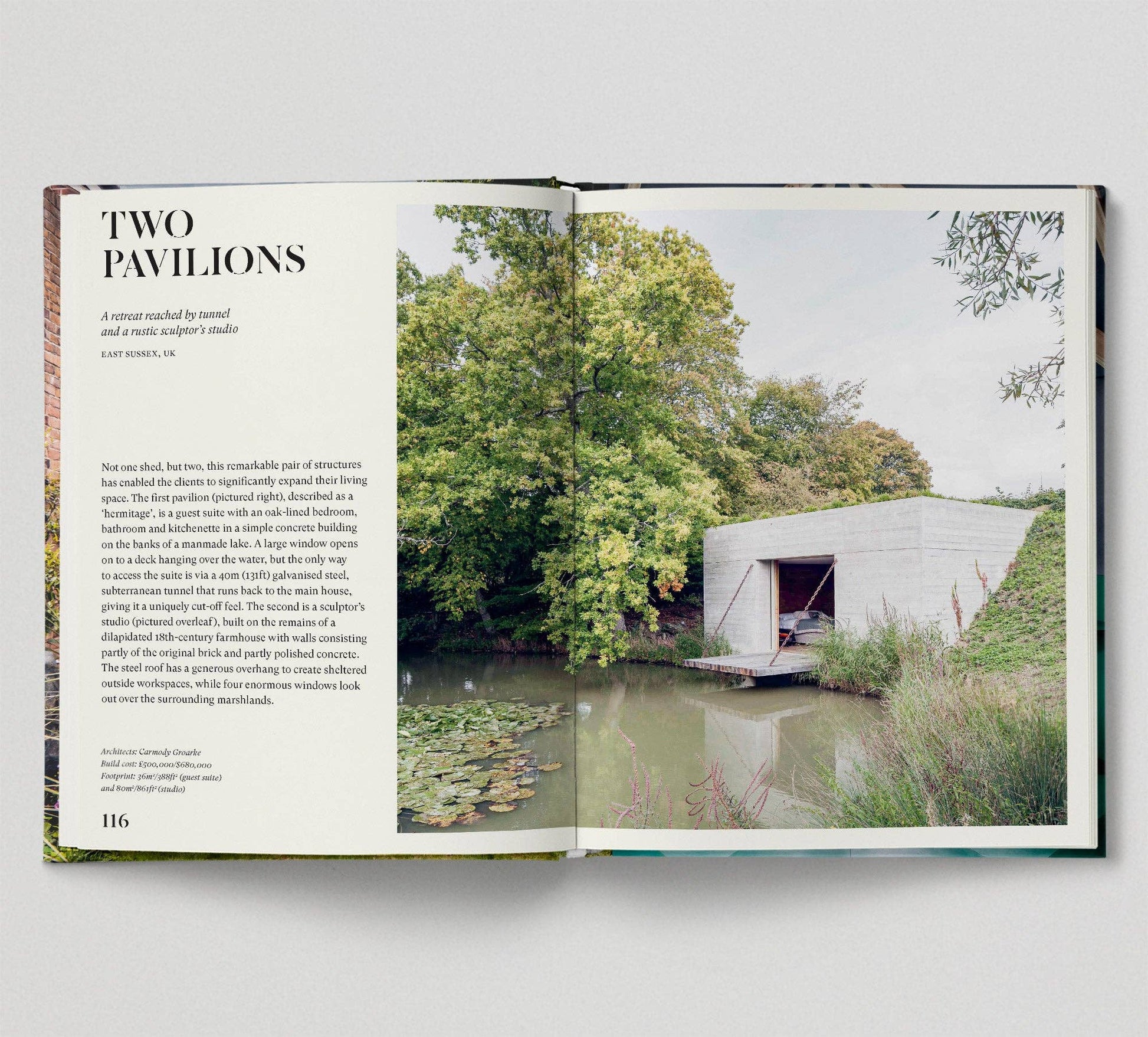 Open book showing a photograph of a modern building by a body of water with trees in the background.