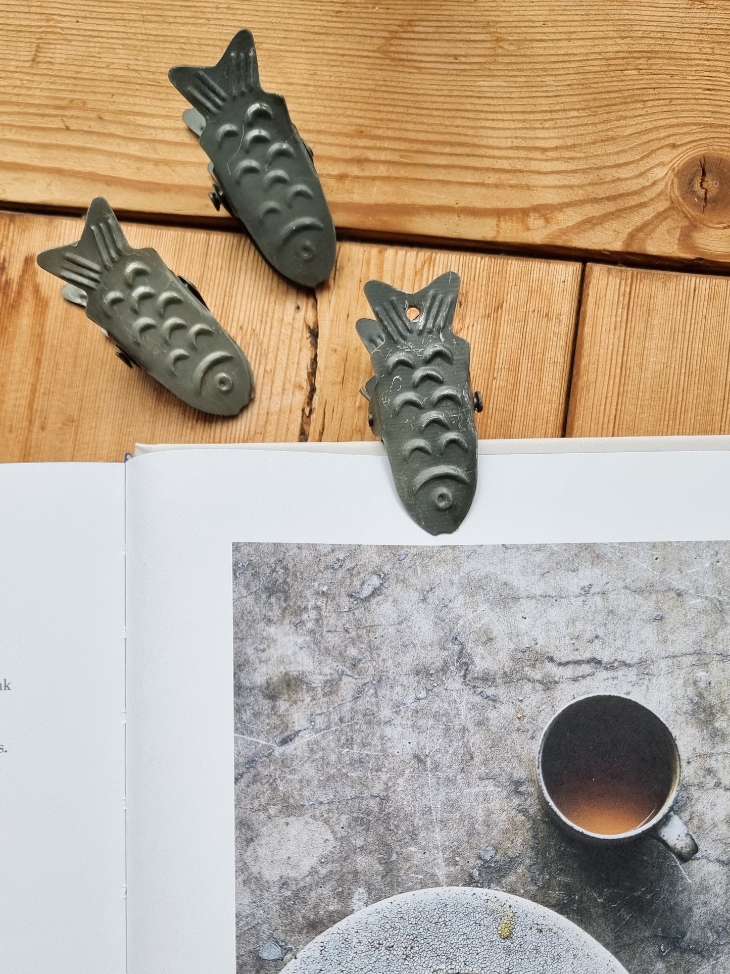 Strömshaga metal fish clips styled on wooden surface with open book and coffee